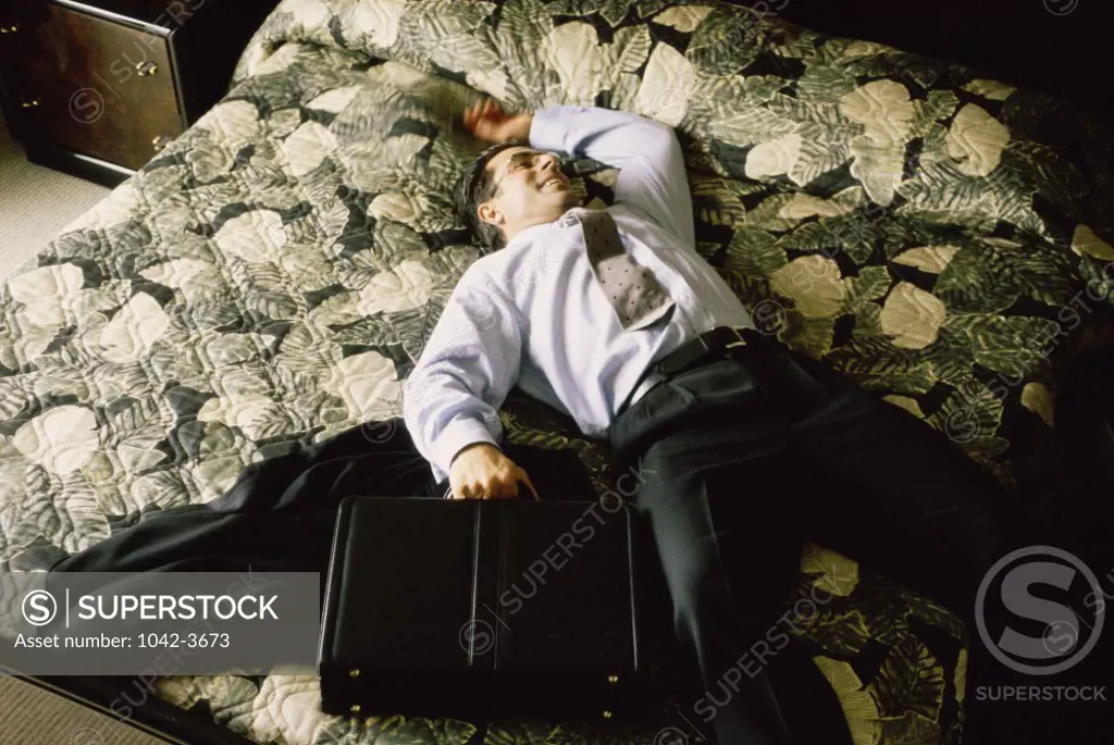 Young businessman lying on a bed