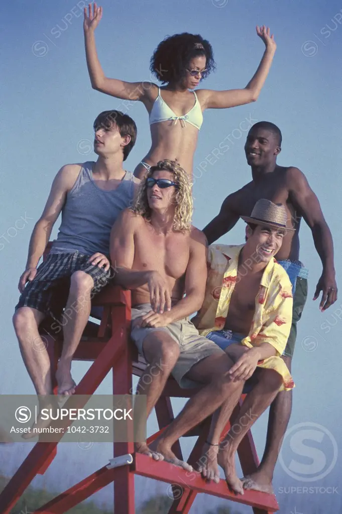 Low angle view of a group of young people sitting on a lifeguard chair