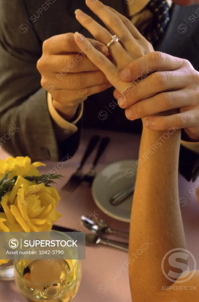 Man placing a wedding band on a woman's finger