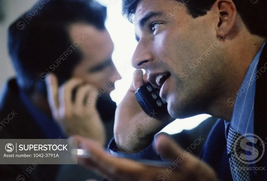 Two businessmen talking on mobile phones