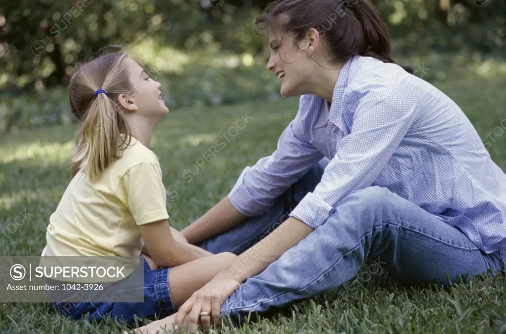 Side profile of a daughter and her mother sitting on a lawn