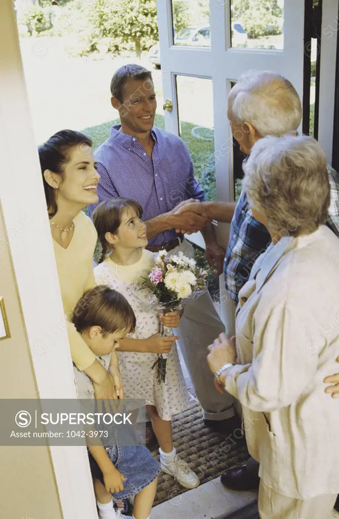 Grandparents greeting their children and grandchildren at the front door