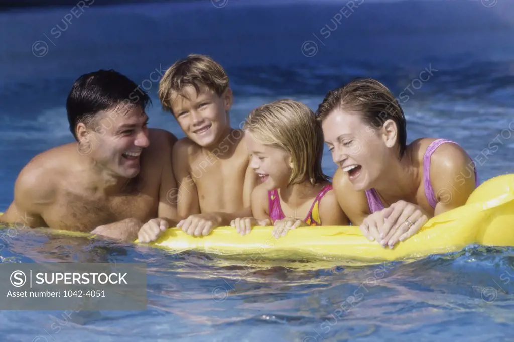 Young couple on a pool raft with their son and daughter