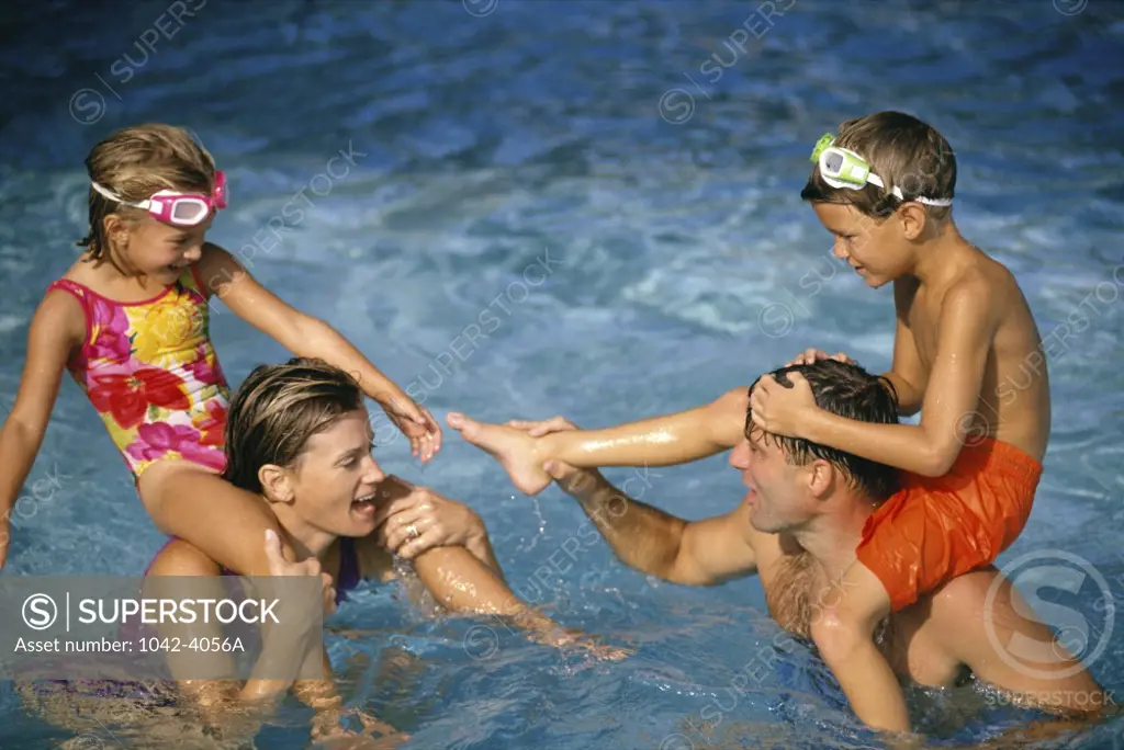 Young couple in a swimming pool with their son and daughter