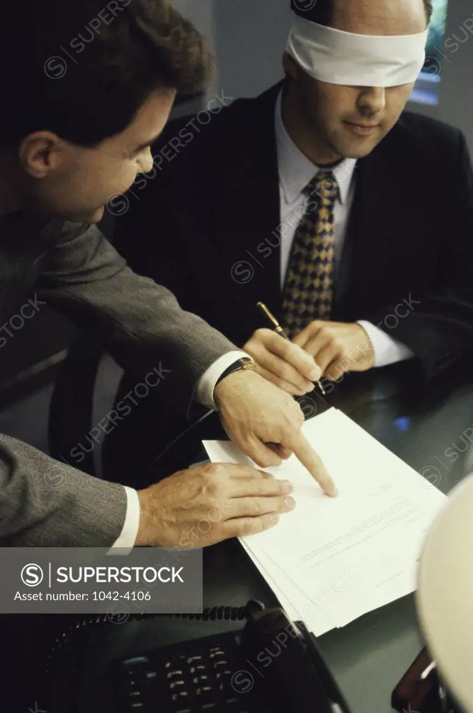 High angle view of a blindfolded businessman signing a document