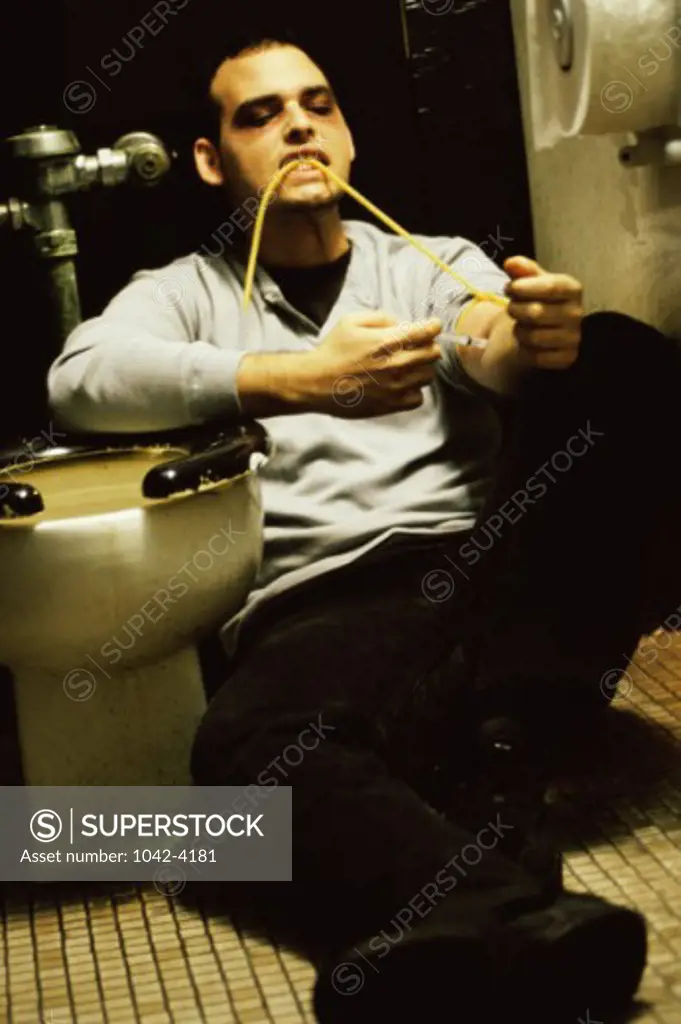 Young man injecting himself in the toilet