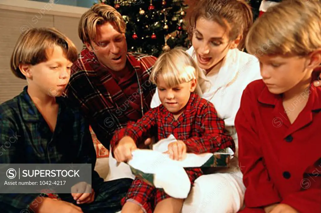 Boy opening a Christmas present with his family