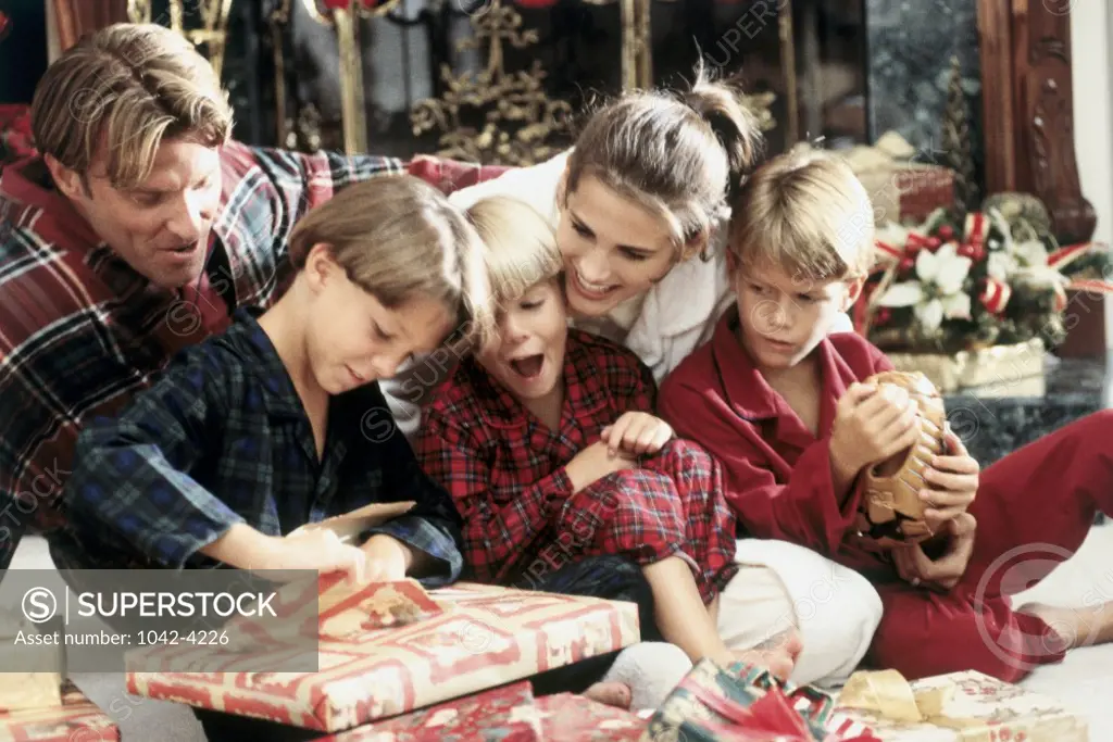 Boy opening a Christmas present with his family