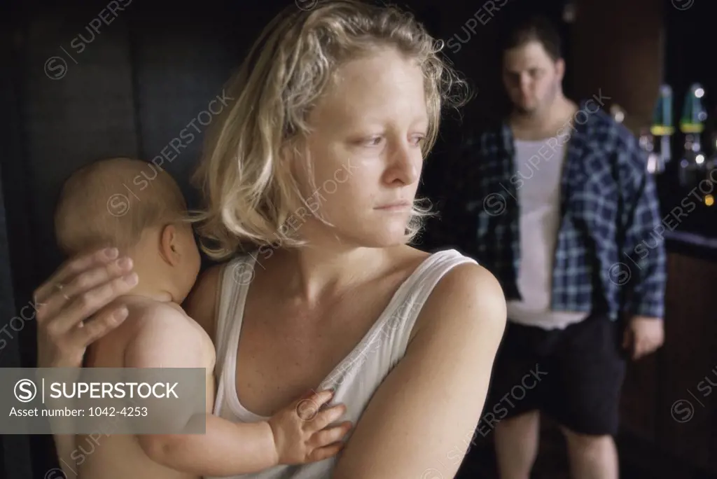 Mother holding her baby boy with a mid adult man standing behind her