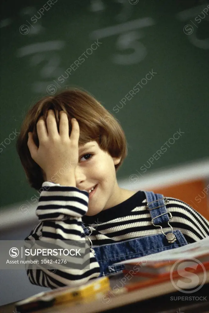 Girl with her hand on her head sitting in a classroom
