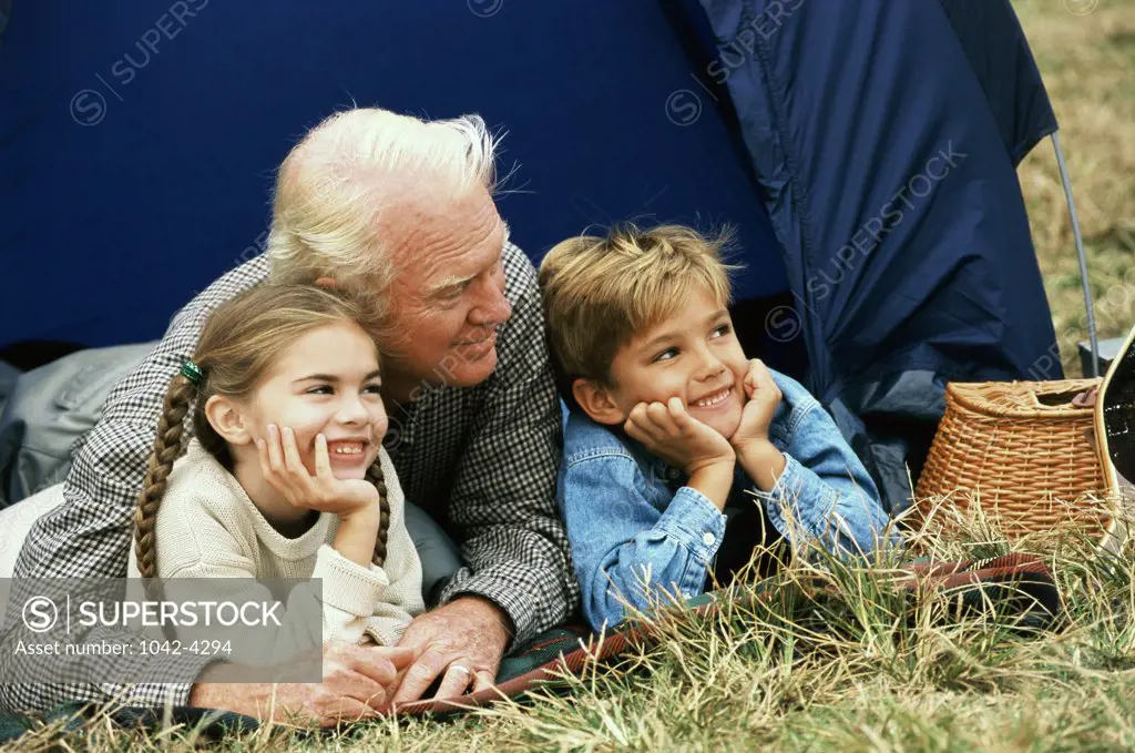 Portrait of an elderly man lying in a tent with his grandchildren