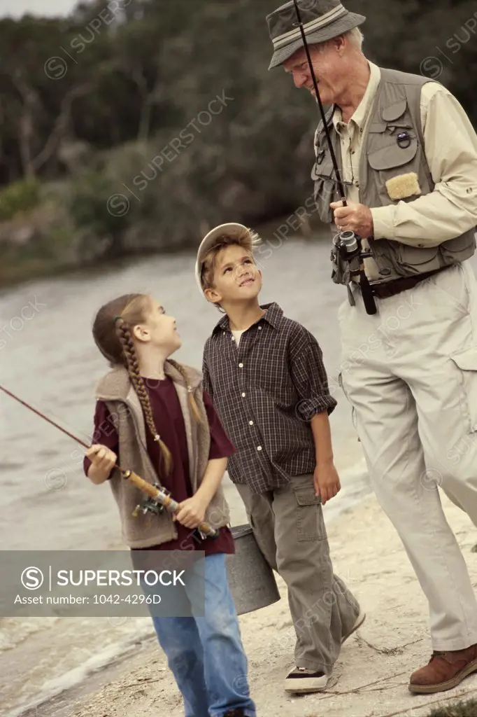 Senior man and his grandchildren carrying fishing rods