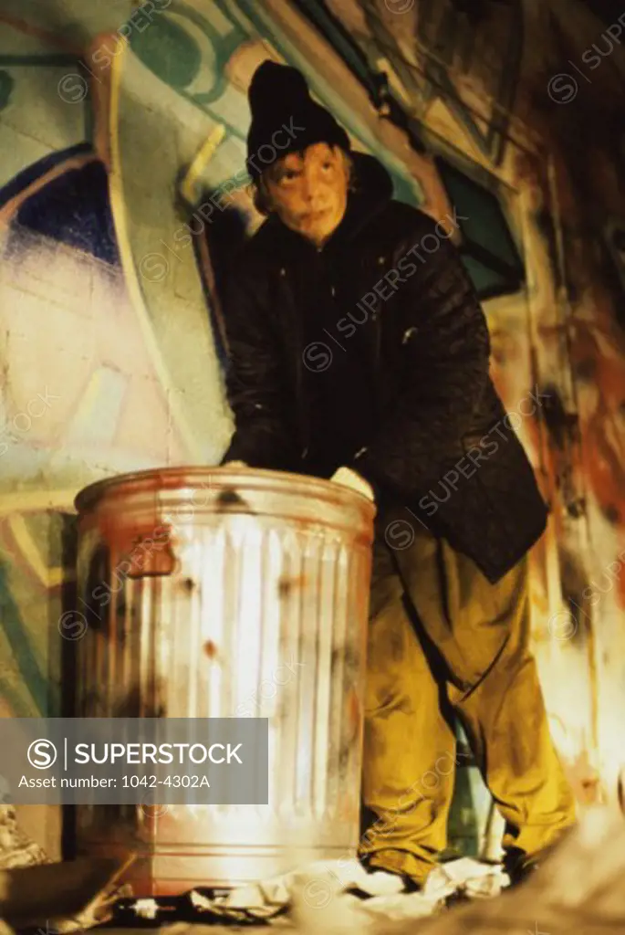Mature man bending over a garbage can full of rubbish
