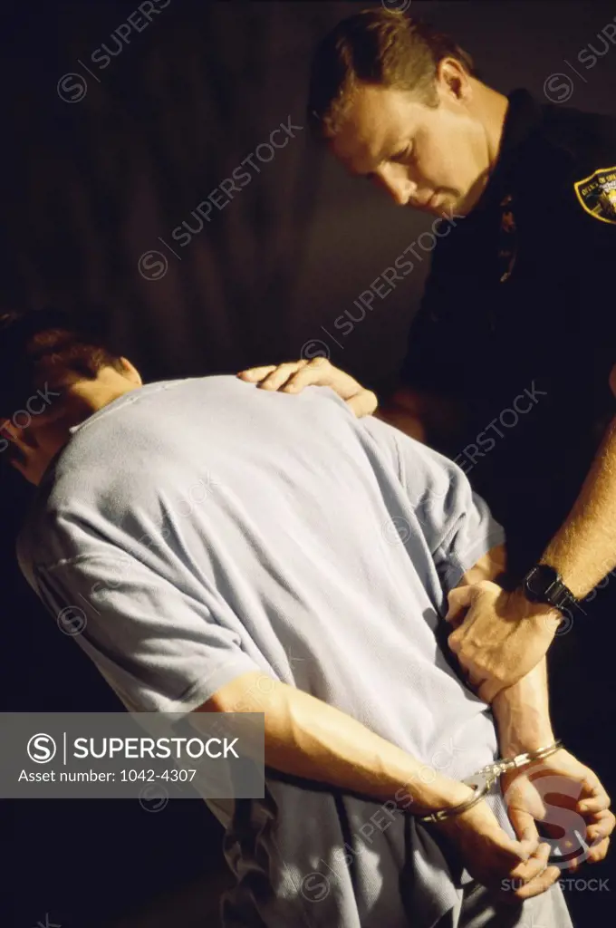 Side profile of a sheriff holding a young man in handcuffs