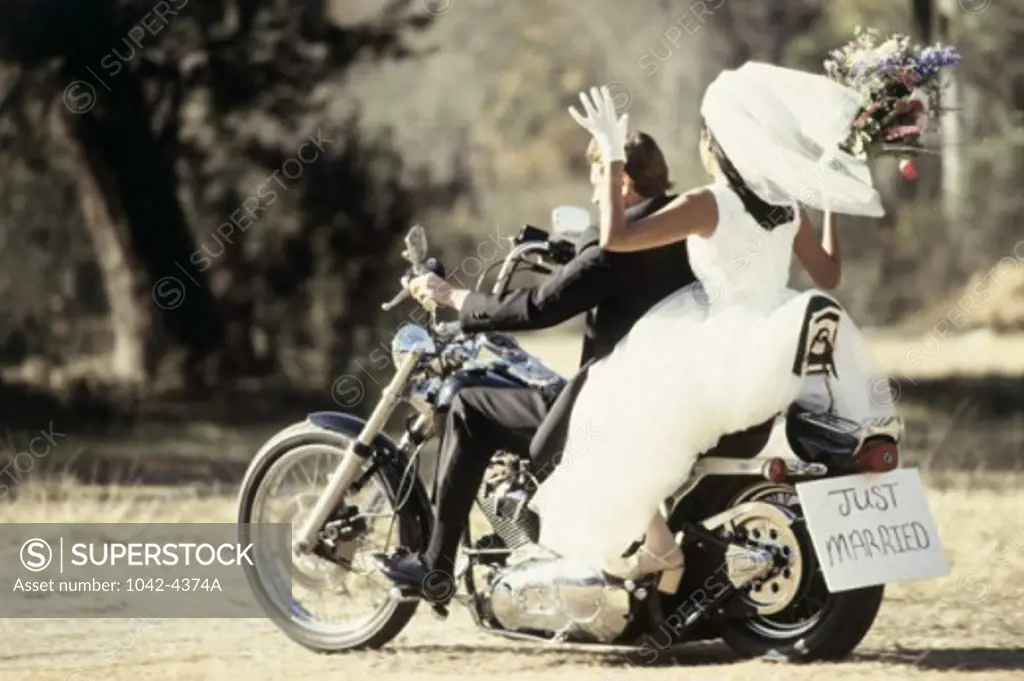 Rear view of a newlywed couple riding on a motorcycle
