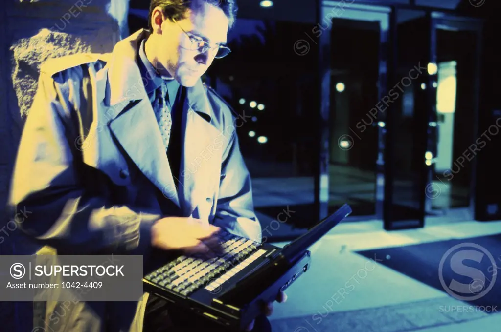Businessman standing outdoors using a laptop