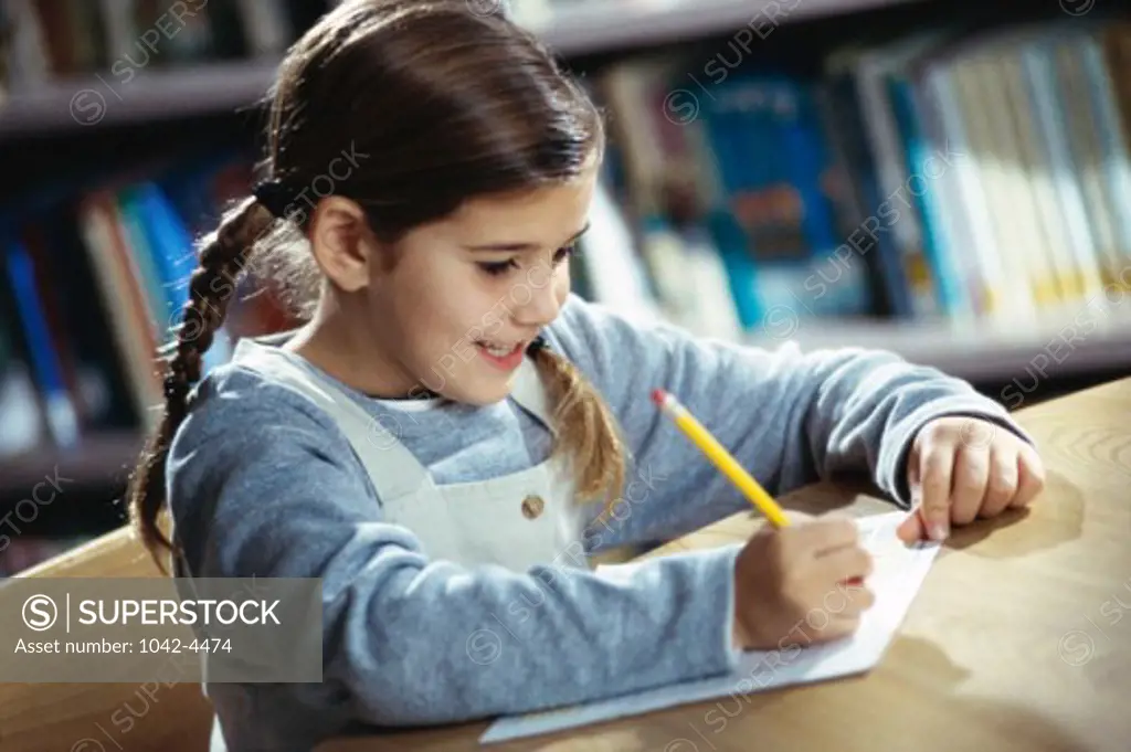Girl writing with a pencil on a sheet of paper