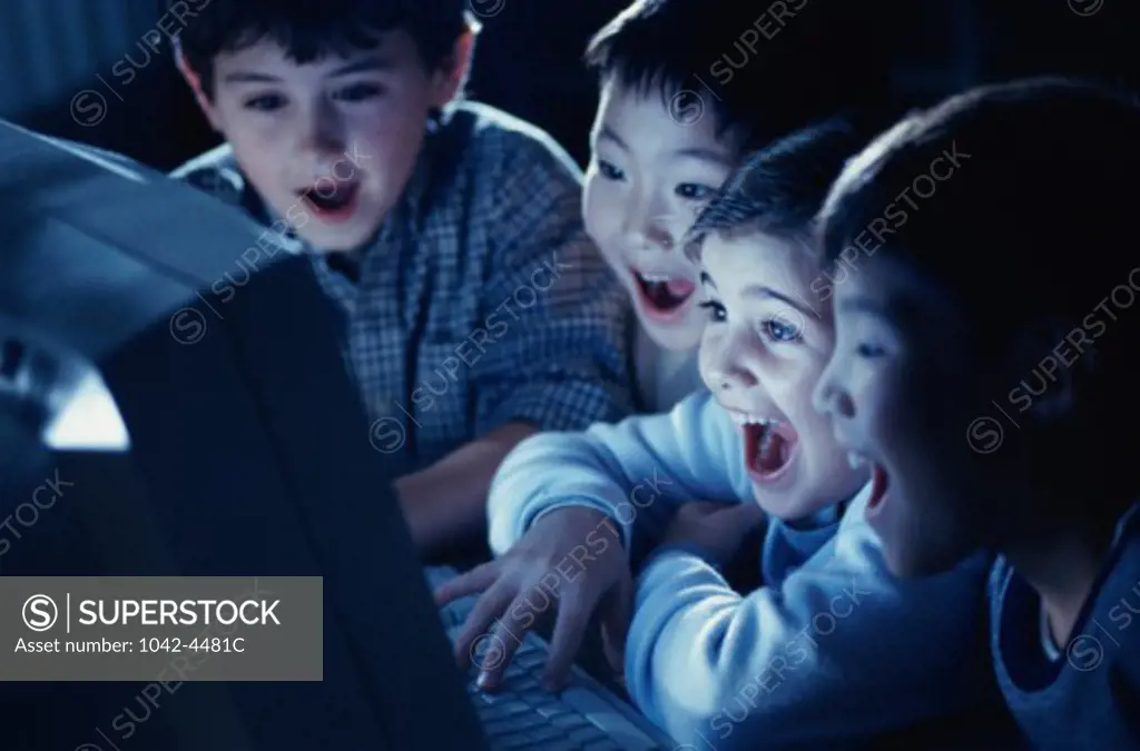 Group of boys laughing in front of a computer monitor