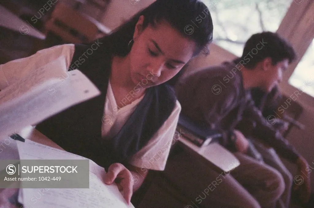 Teenage girl holding sheets of papers in a classroom