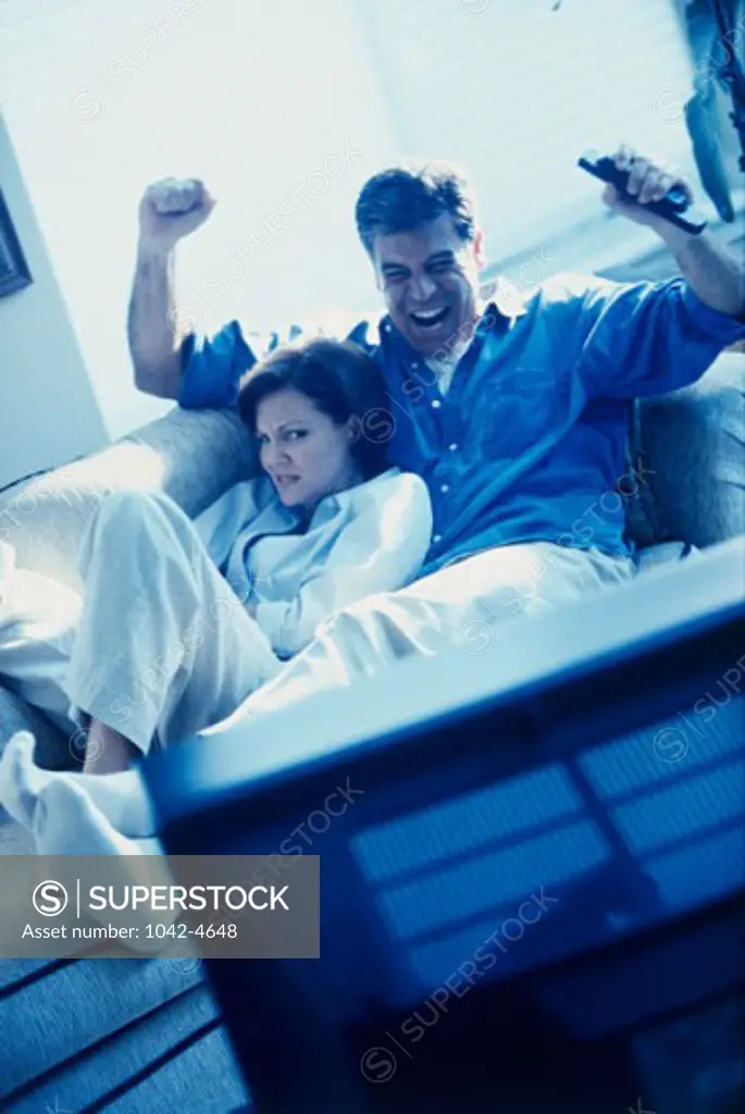 Mid adult couple sitting on a couch and watching television