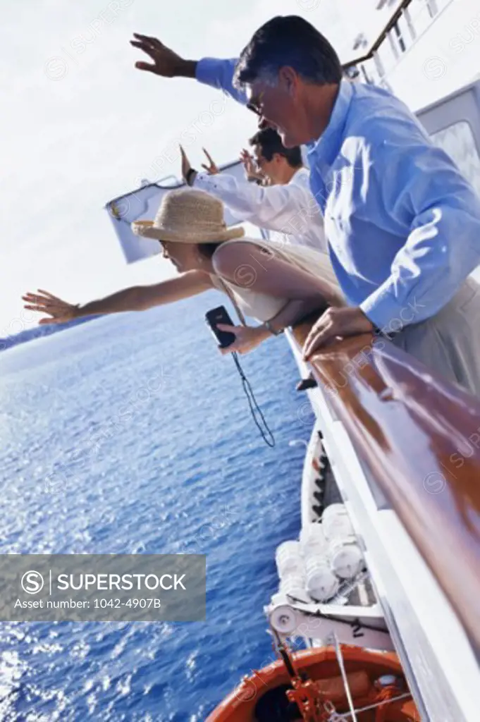 Side profile of a group of people standing on a cruise ship waving