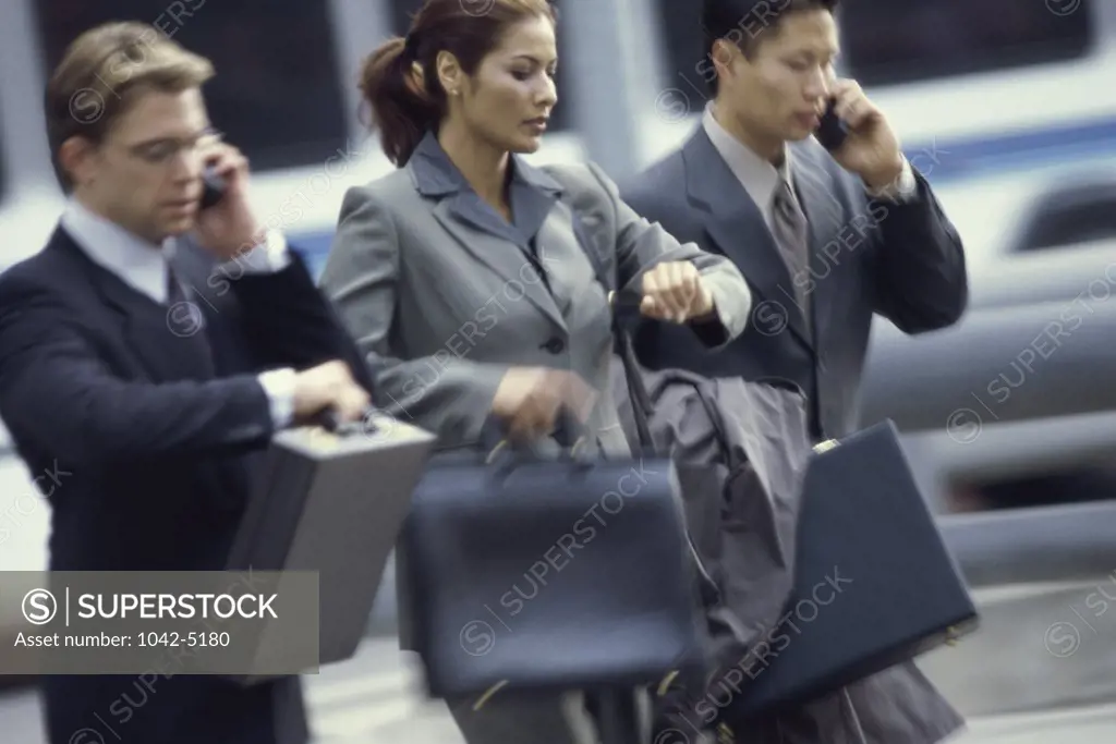 Two businessmen and a businesswoman walking side by side