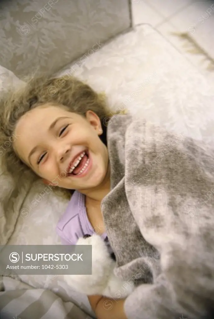 High angle view of a girl lying on a couch laughing