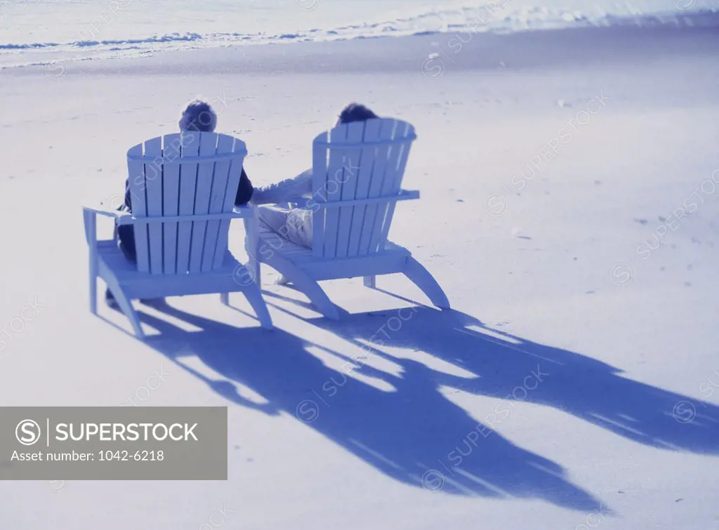 Senior couple sitting on deck chairs on the beach