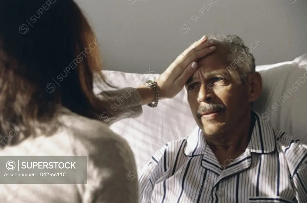Close-up of a female doctor touching a male patient's forehead