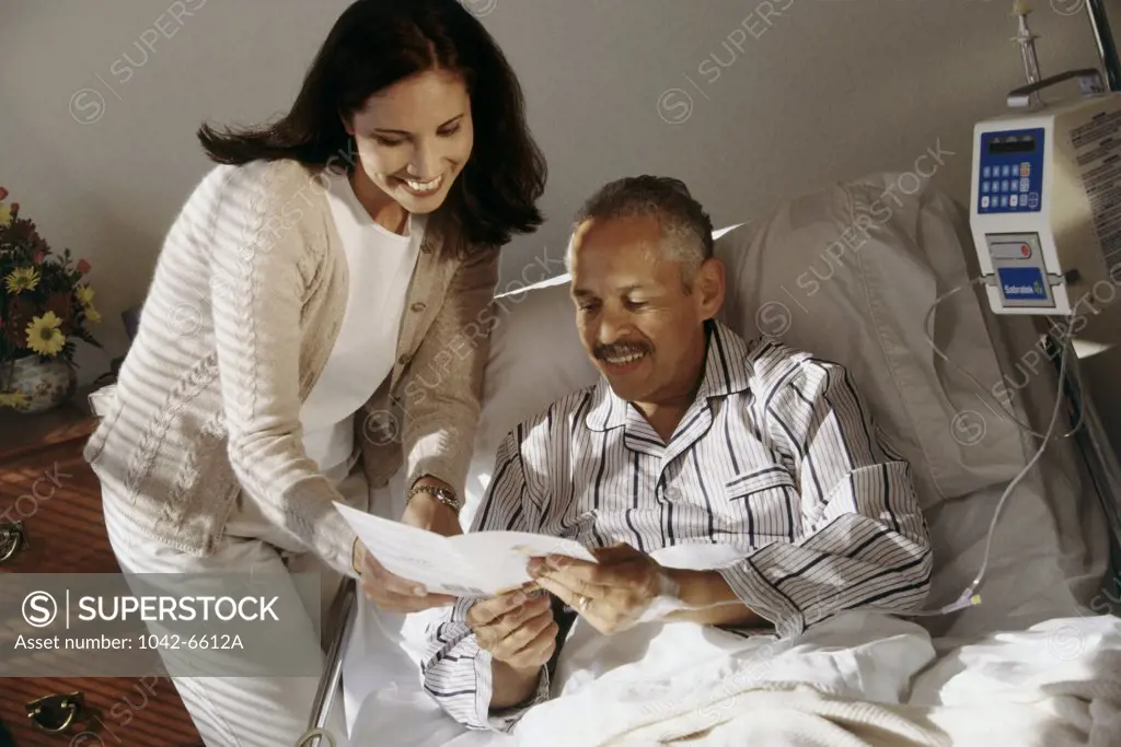 Senior man reading a get well card with a young woman standing near him