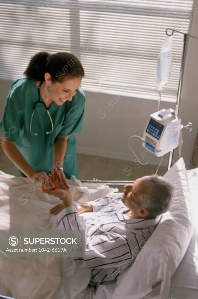 High angle view of a female nurse giving pills to a male patient