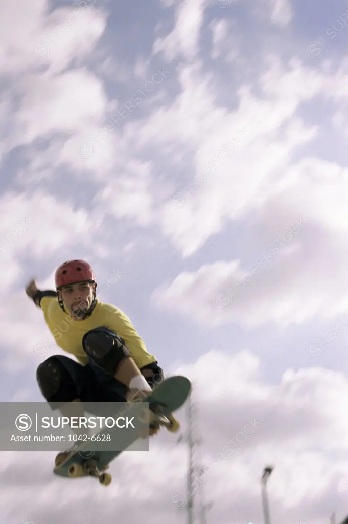 Low angle view of a young man skateboarding in mid air