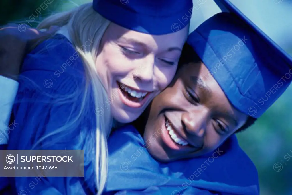 Two young graduates hugging each other