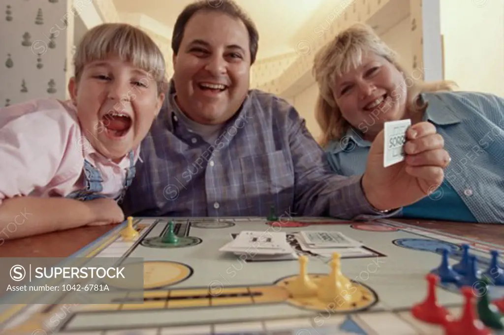 Portrait of parents and their daughter playing a board game