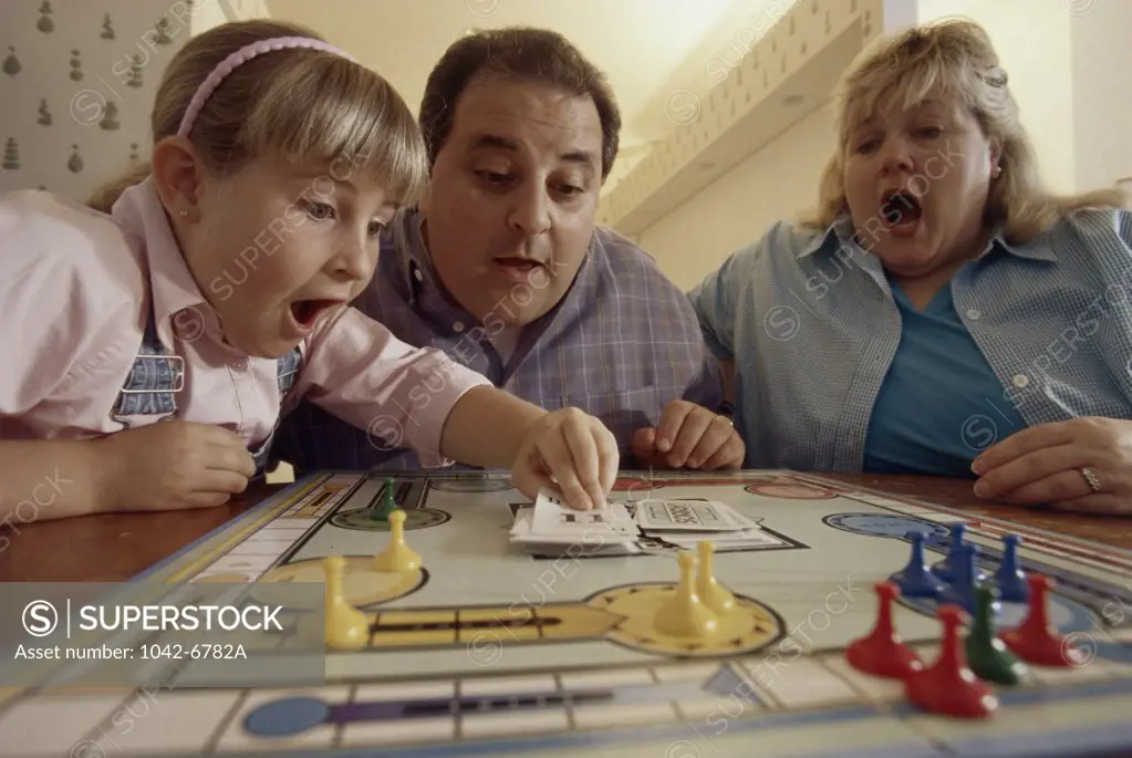 Close-up of parents and their daughter playing a board game