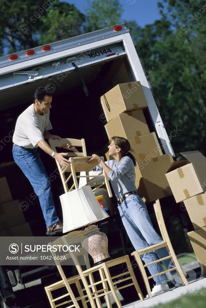 Mid adult couple unloading cardboard boxes from a moving van