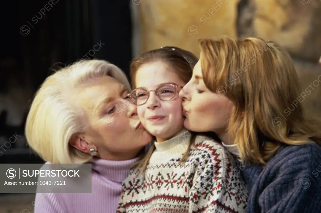Mother and grandmother kissing a girl