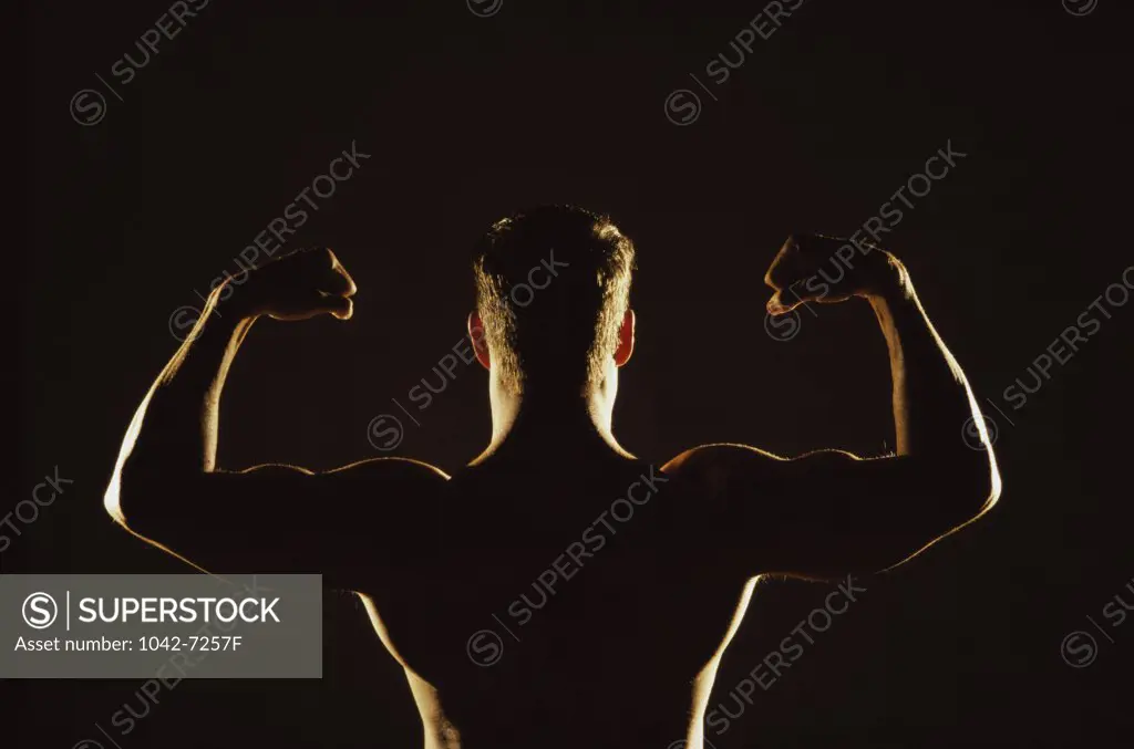 Rear view of a young man flexing his muscles