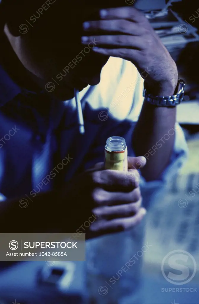 Young man smoking a cigarette while holding a bottle of alcohol