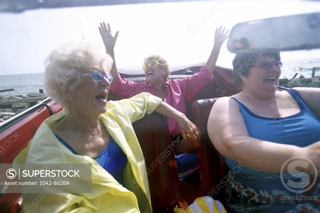 Three senior women traveling together in a convertible car