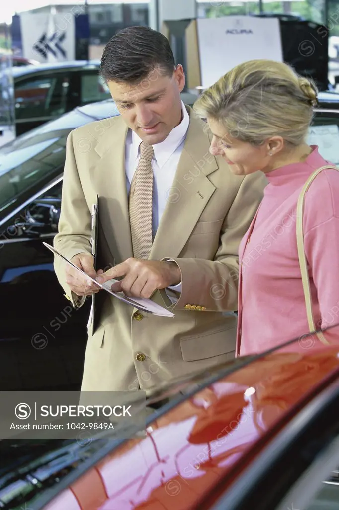 Car salesman showing a mid adult woman a brochure