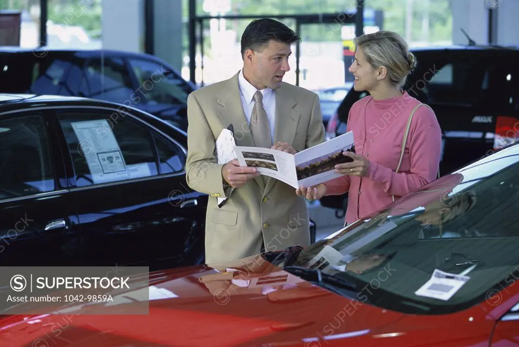 Car salesman showing a mid adult woman a brochure
