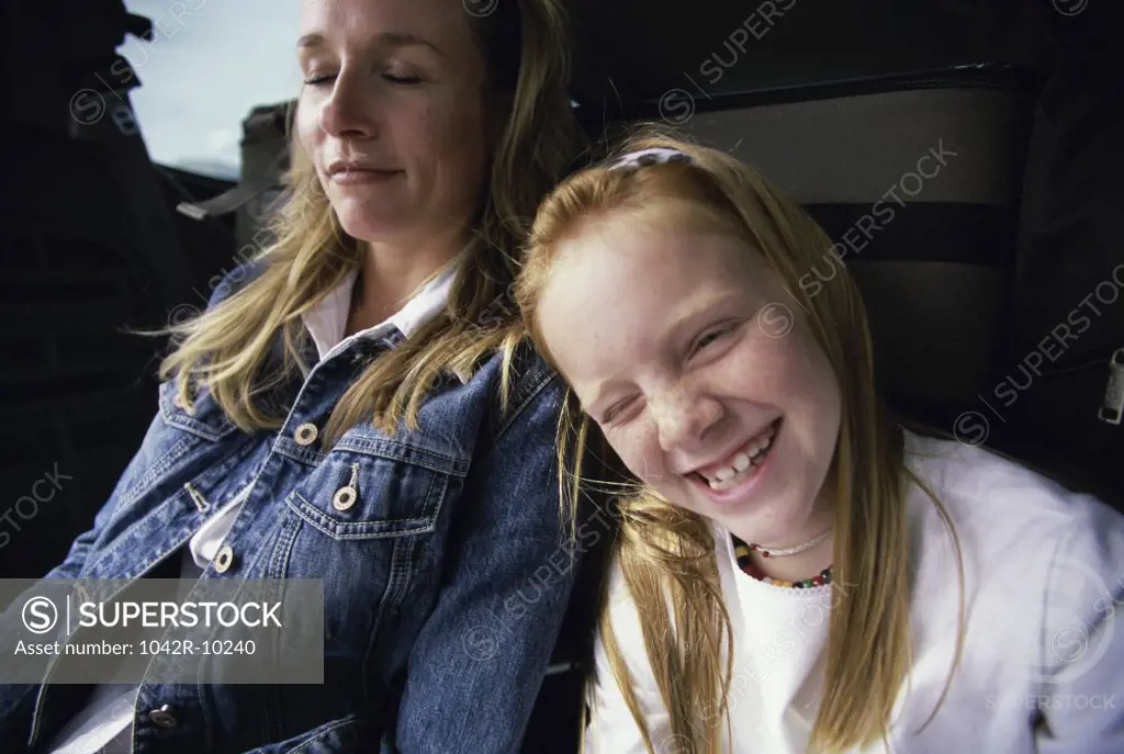 Close-up of girl smiling and sitting near her mother