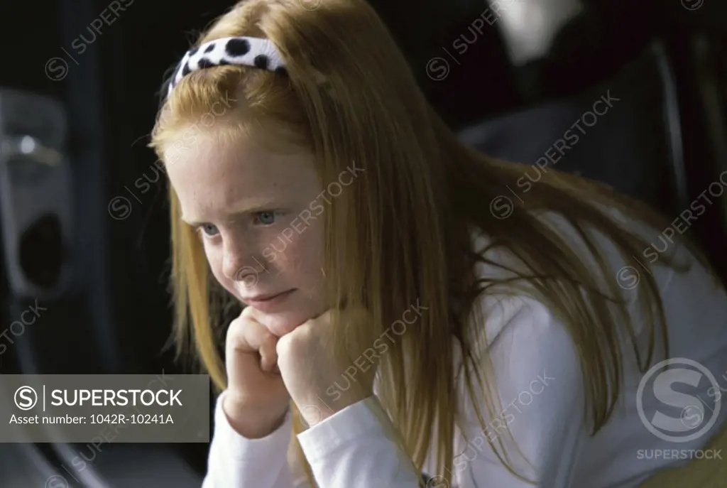 Side profile of a girl sitting with her hands on her chin
