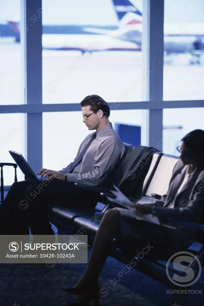 Side profile of a businessman and a businesswoman sitting in an airport lounge