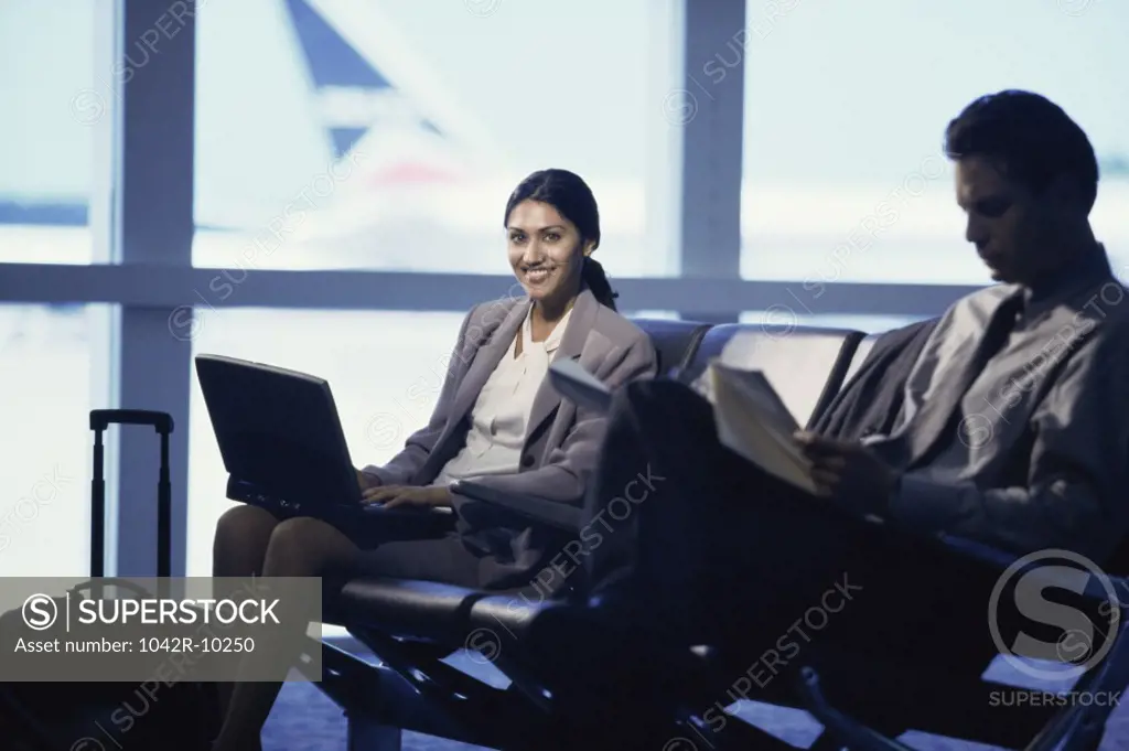 Portrait of a young woman sitting at an airport lounge next to a man