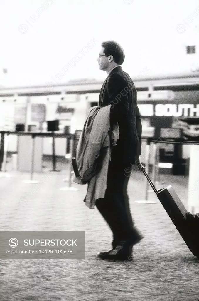 Side profile of a businessman pulling a suitcase