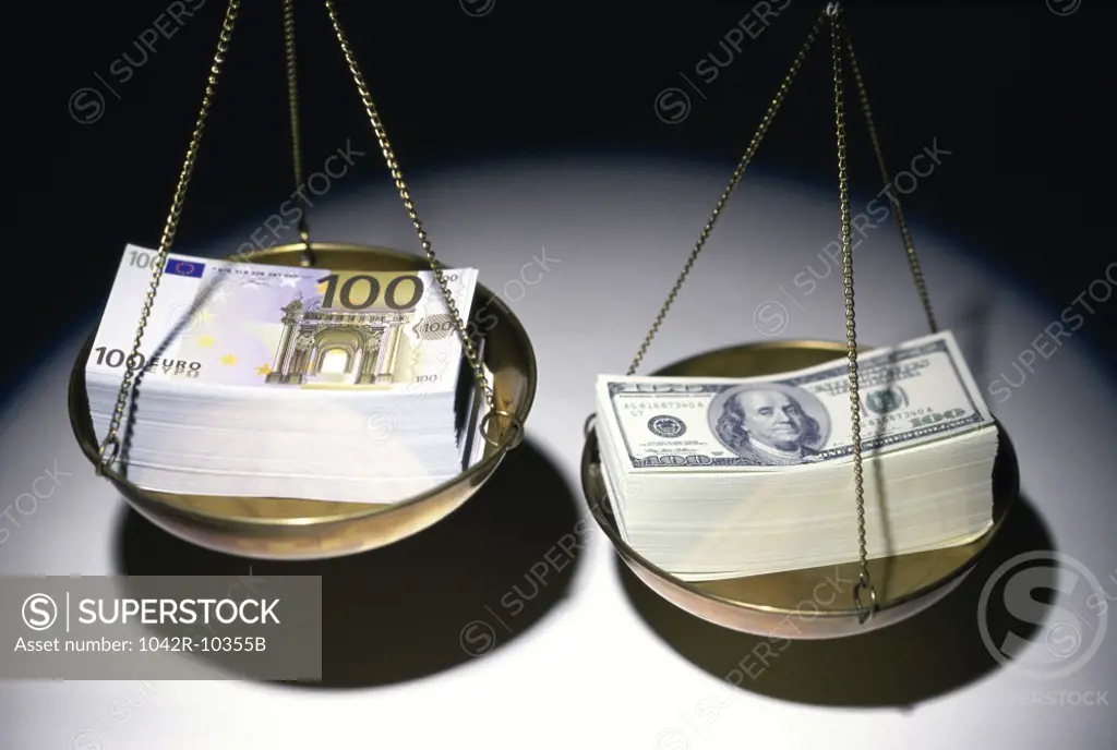 Stack of Euro and American dollar bills on a balance scale