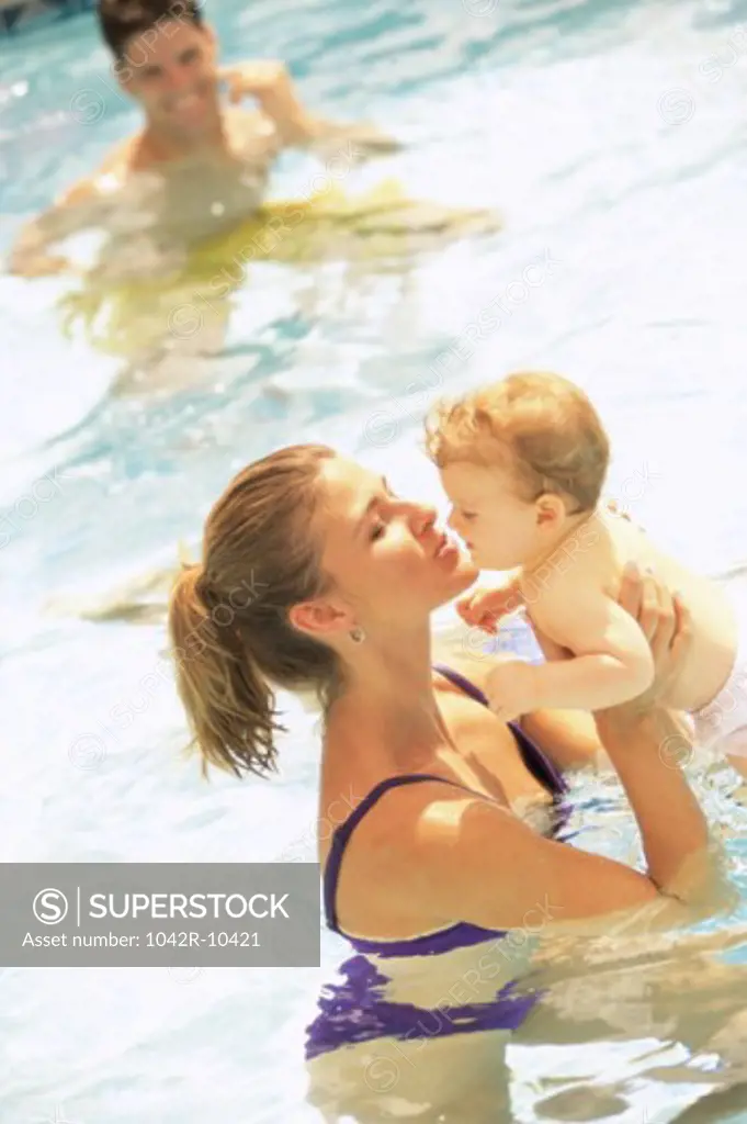 Mother holding her baby girl in a swimming pool