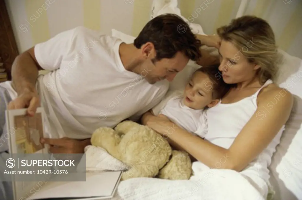 Father and mother lying in bed with their son